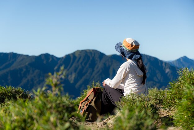 La mujer de la caminata se sienta en la cima de la montaña