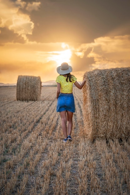 Una mujer con una camisa amarilla camina por un campo de heno.