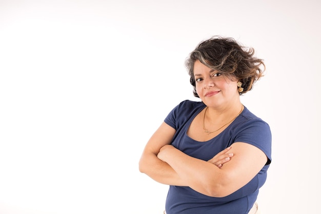 Foto una mujer con una camisa azul y un collar está de pie con los brazos cruzados