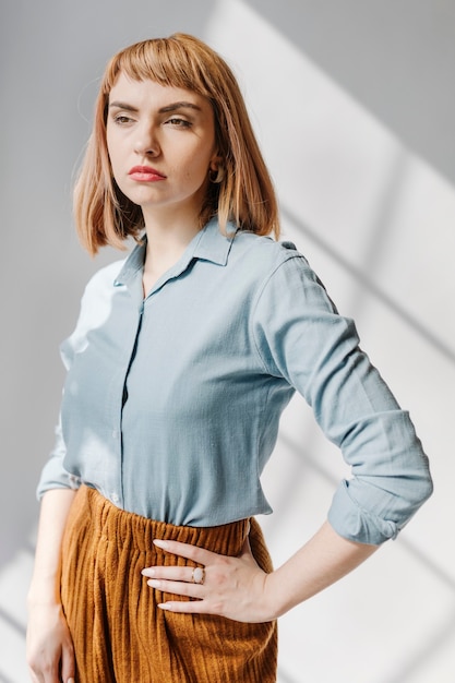 Mujer con una camisa azul junto a la pared blanca