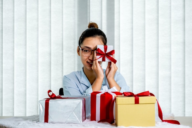 Mujer con una camisa azul sosteniendo una caja de regalo blanca atada con una cinta roja presente