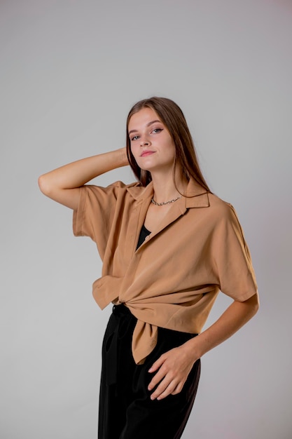 Foto mujer con camisa beige con cuello y pantalón negro