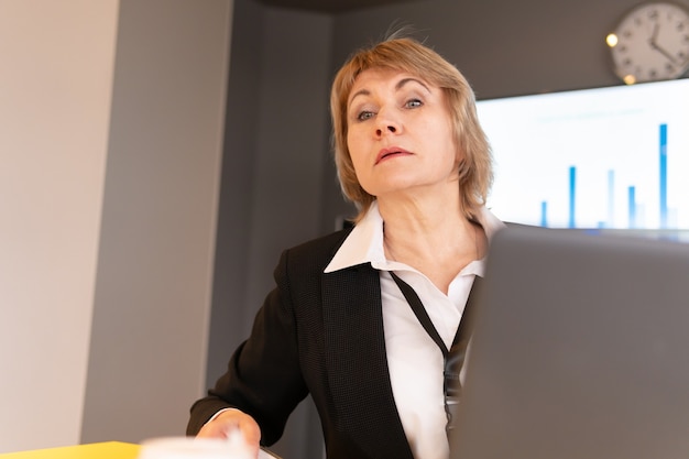 Una mujer con una camisa blanca está entrenando a los oyentes en la sala de negocios.