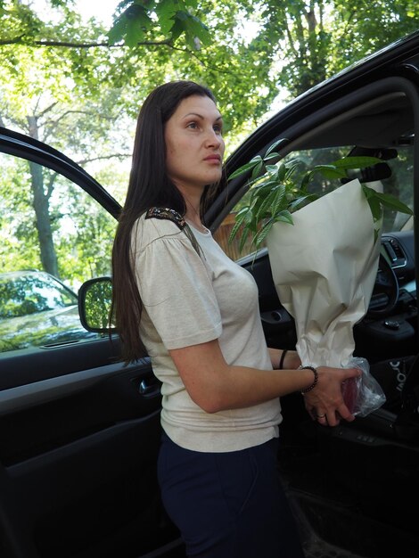 Una mujer con una camisa blanca está de pie en un automóvil con una bolsa que dice "soy una dama"