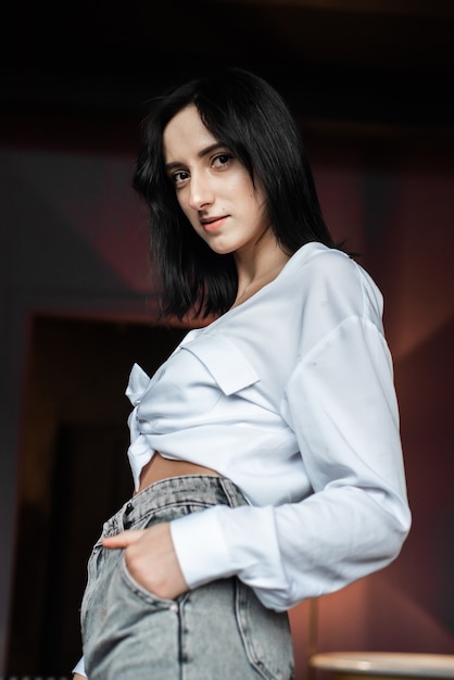 Mujer con camisa blanca y jeans en casa