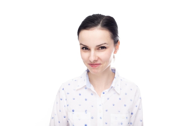 Foto una mujer con una camisa blanca con lunares azules sonríe misteriosamente de fondo blanco