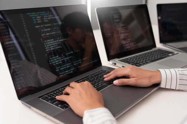 mujer con camisa blanca a rayas trabajando frente a computadoras portátiles