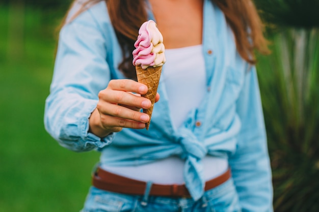 Mujer en camisa comiendo helado dulce al aire libre en un caluroso día de verano