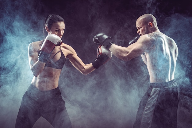 Mujer sin camisa haciendo ejercicio con un entrenador en la lección de boxeo y defensa personal Lucha femenina y masculina