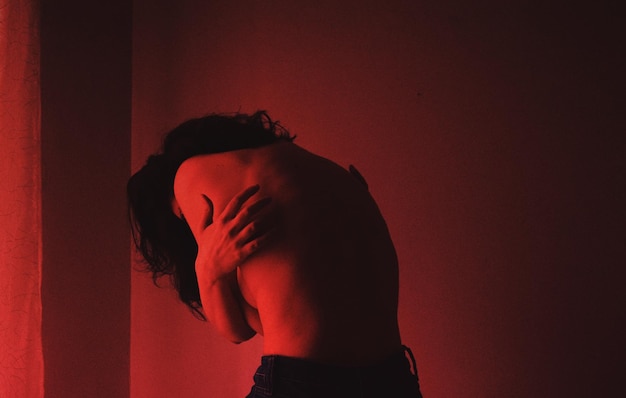 Mujer sin camisa de pie contra la pared