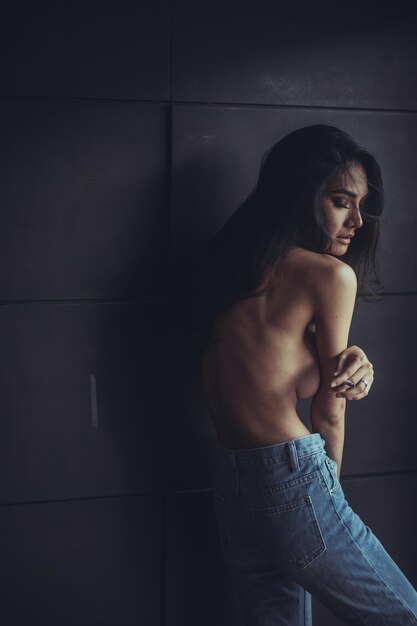 Foto mujer sin camisa de pie junto a la pared