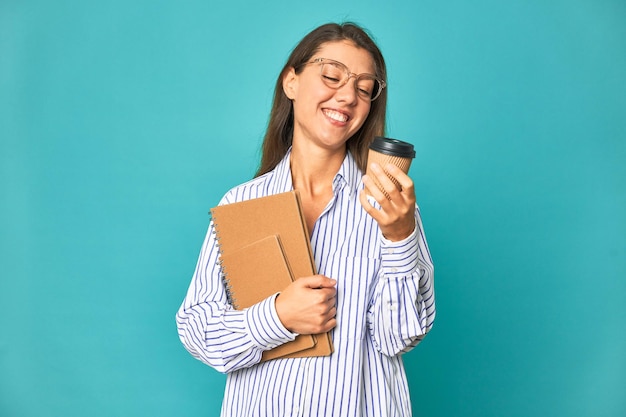 Una mujer con una camisa a rayas sostiene una taza de café y mira su teléfono.