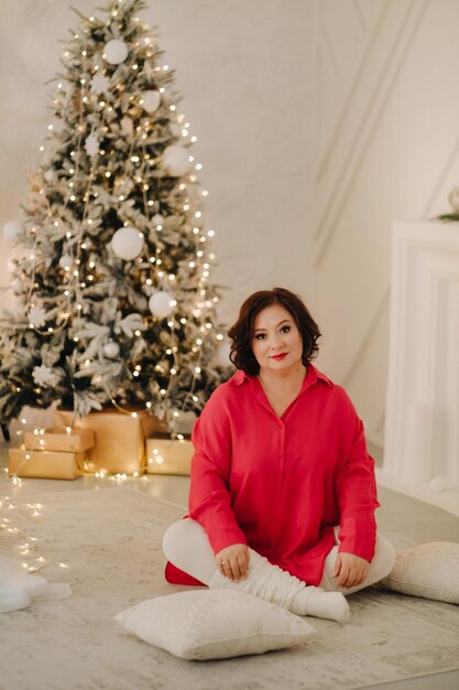 Una mujer con una camisa roja en una habitación decorada para el ambiente de Año Nuevo en casa de Navidad