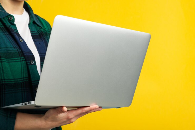 Foto mujer en camisa tiene laptop sobre superficie amarilla