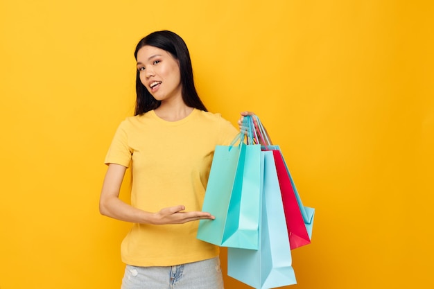 Mujer en una camiseta amarilla con bolsas de compras multicolores fondo aislado inalterado