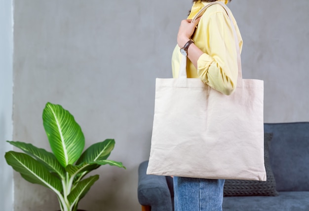 Mujer en camiseta amarilla casual con soporte y bolsa de tela de lona para logotipo.