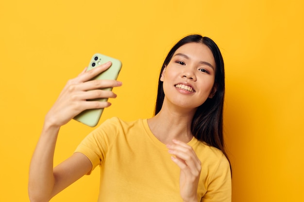 Mujer en una camiseta amarilla mirando el teléfono posando modelo de estudio inalterado