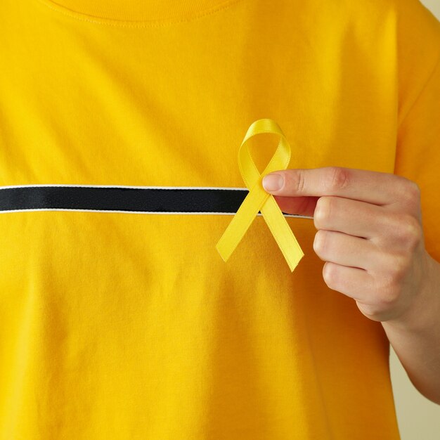 Mujer en camiseta amarilla sostiene cinta de concienciación sobre el cáncer infantil