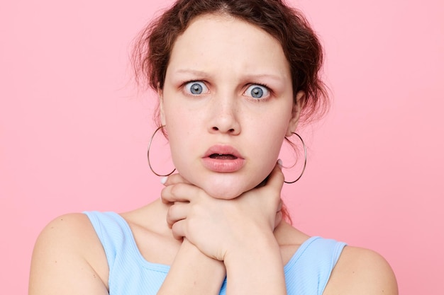 Mujer en camiseta azul se estrangula emociones fondo rosa