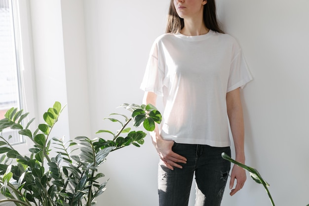 Mujer con camiseta blanca en blanco con espacio para su logotipo, maqueta o diseño en interiores