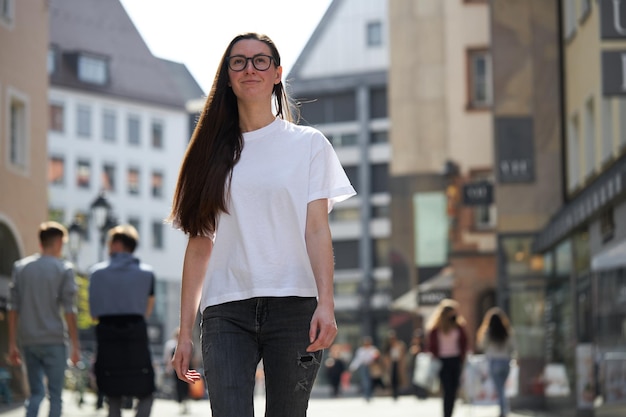 Mujer con camiseta blanca en blanco con gafas en la ciudad