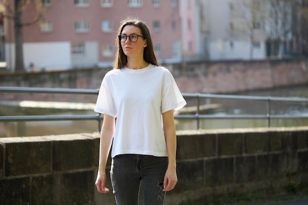 Mujer con camiseta blanca en blanco con gafas en la ciudad