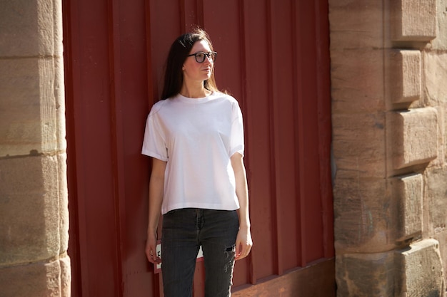 Mujer con camiseta blanca en blanco con gafas en la ciudad