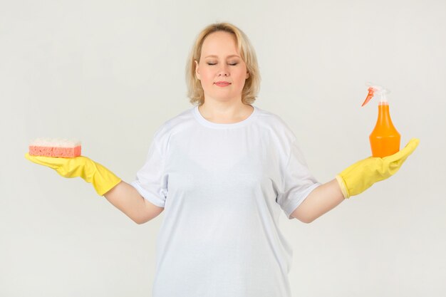 Foto mujer en una camiseta blanca con guantes de goma con una esponja y spray