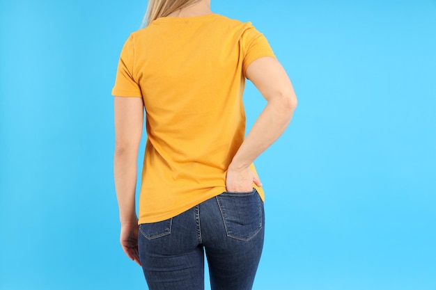 Mujer en camiseta naranja en blanco sobre fondo azul.