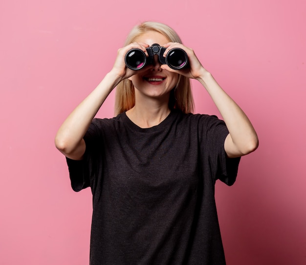 Mujer en camiseta negra con binoculares en rosa