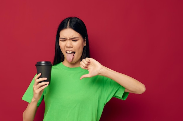 Mujer en una camiseta verde de cristal negro con una bebida disgustada