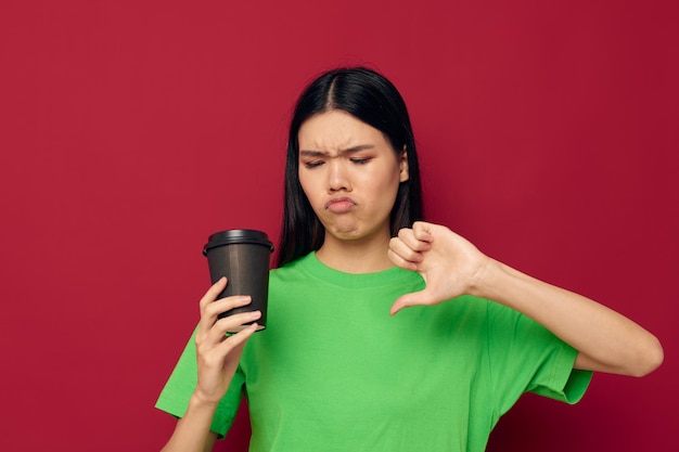 Mujer en una camiseta verde de cristal negro con una bebida disgustada