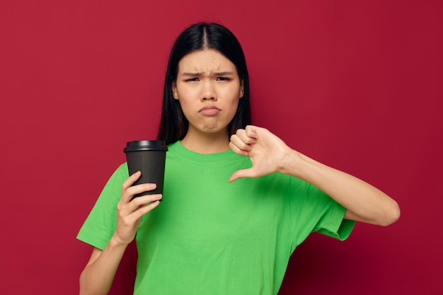 Mujer en una camiseta verde de cristal negro con una bebida disgustada