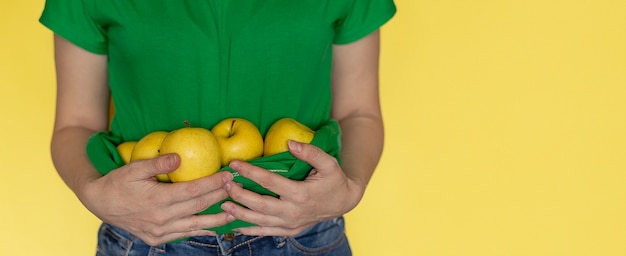 Mujer en camiseta verde tiene manzana en manos en amarillo