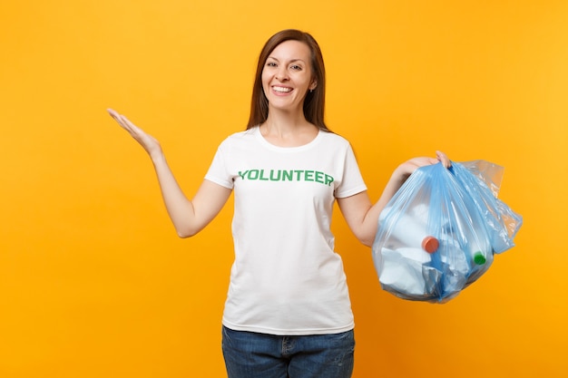 Mujer en camiseta voluntaria, bolsa de basura aislada sobre fondo amarillo. Ayuda de asistencia voluntaria gratuita, gracia benéfica. Problema de contaminación ambiental. Detener el concepto de protección del medio ambiente de basura de la naturaleza.