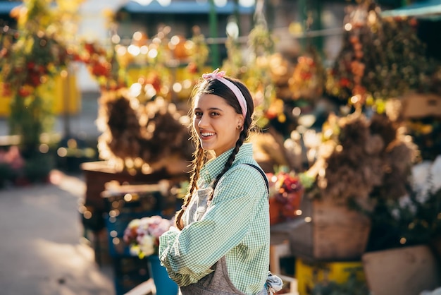 Mujer campesina feliz con overoles de mezclilla sonriendo sinceramente mientras posa