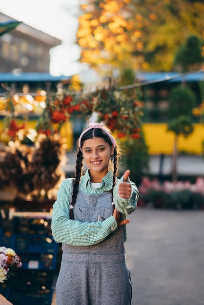 Mujer campesina con overoles de mezclilla sonriendo sinceramente mostrando el pulgar hacia arriba