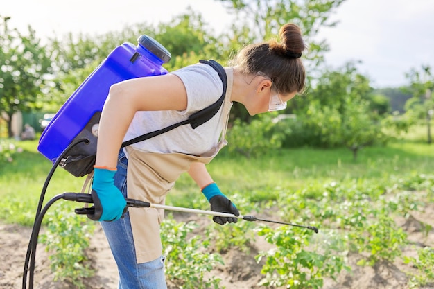 Mujer campesina rociando plantas de patata en un huerto