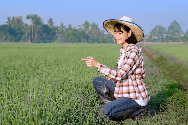 Una mujer campesina sentada en un campo posa con un dedo acusador y una cara sonriente.