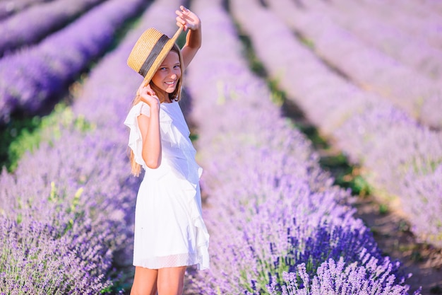 Mujer en campo de flores de lavanda al atardecer en vestido blanco y sombrero