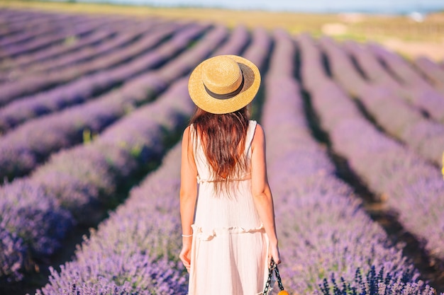 Mujer en campo de flores de lavanda en vestido blanco y sombrero