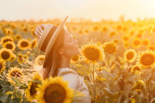 Mujer en el campo de girasoles chica feliz con un sombrero de paja posando en un vasto campo de girassoles al atardecer