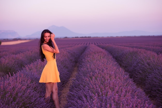 mujer de campo de lavanda con vestido amarillo divirtiéndose y relajándose en el campo de flores púrpura