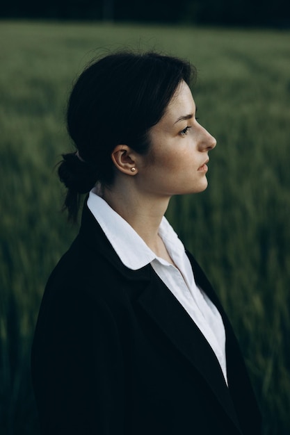 Una mujer en un campo mirando a otro lado de la cámara.