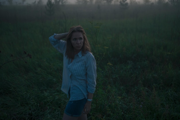 Foto mujer en un campo con niebla brumosa