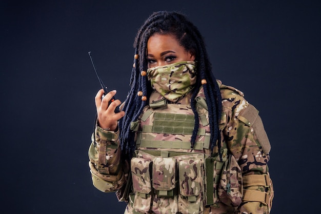 Mujer en un camuflaje militar con un soldado latino del ejército afroamericano de radio en ropa de camuflaje rastas de pelo maquillaje de noche sobre un fondo negro en el estudio