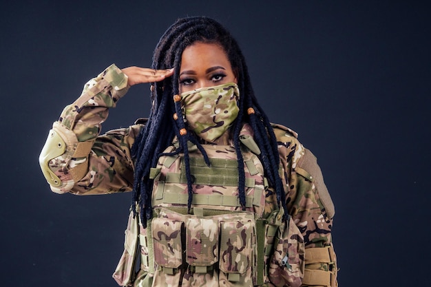 Mujer en un camuflaje militar con un soldado latino del ejército afroamericano de radio en ropa de camuflaje rastas de pelo maquillaje de noche sobre un fondo negro en el estudio