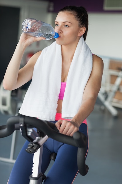 Mujer cansada de agua potable mientras se trabaja en la clase de spinning