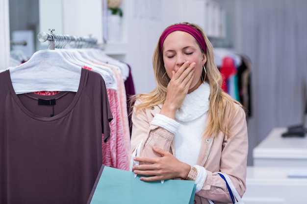 Mujer cansada con bolsas de compras bostezando