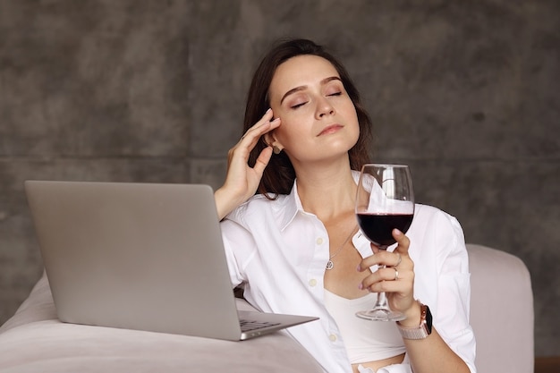 Mujer cansada después del trabajo bebe una copa de vino tinto